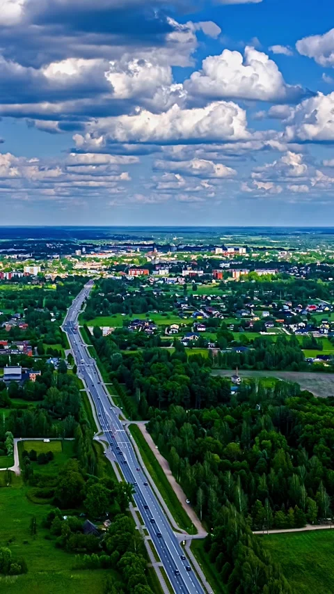 White cumulus clouds drift rapidly over green residential areas, houses, and Stock Footage 345131149