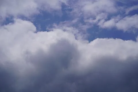White cumulus clouds floating in a bright blue sky during a sunny day Stock Photos