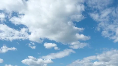 White cumulus clouds floating gently across a bright blue sky Stock Footage 283066069