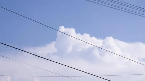 White Cumulus Clouds With Overhead Power Lines Against Blue Sky Stock Photos