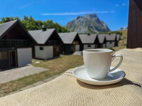 White cup on a background of mountain and cottages. Coffee break Stock Photos
