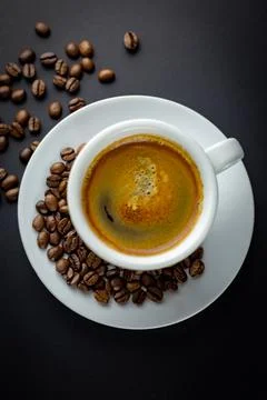White cup of black coffee with coffee beans around. Black background. Stock Photos