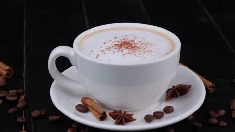 White cup with black coffee sprinkled on top with chocolate or cocoa on a dark Stock Footage 197572475