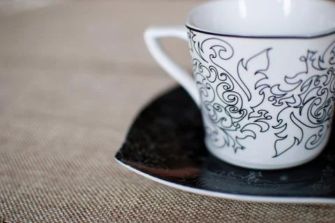 White cup with black patterns on the table covered with cloth Foto stock