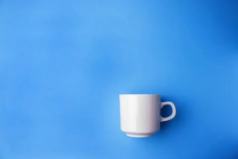 White cup on blue background Stock Photos