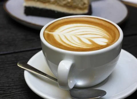 White cup of caffe latte with rosetta latte art, teaspoon and saucer Stock Photos