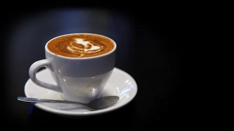 A white cup of cappuccino coffee with a pattern from cinnamon on Stock Photos