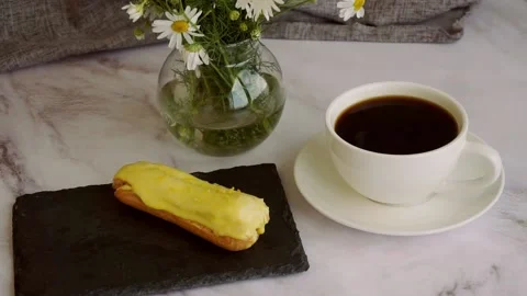 A white cup of coffee and lemon eclairs on a black stand. Stock Footage 204740208