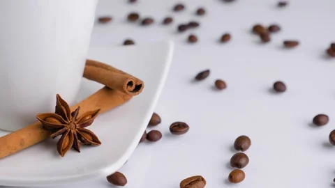 White cup with coffee beans and cinnamon sticks rotating on a white background. Stock Footage 131005171