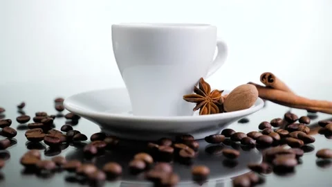 White cup with coffee beans and cinnamon sticks rotating over white background. Stock Footage 131005453