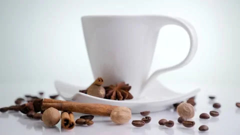 White cup with coffee beans and cinnamon sticks rotating on a white background. Stock Footage 131005820