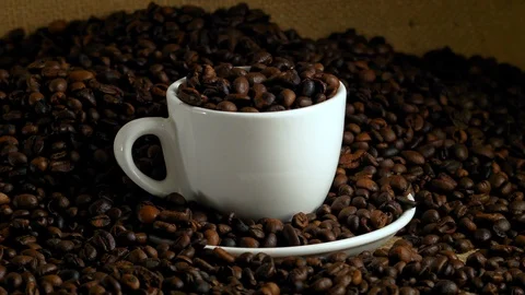 White cup with coffee beans, fried coffee beans on burlap Stock Footage 85594856
