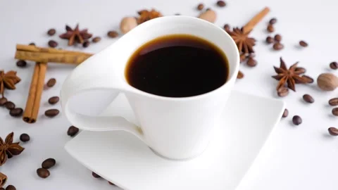 White cup of coffee with coffee beans and spices rotating on a white background. Stock Footage 130254418