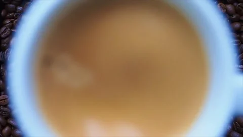 White cup of coffee falling down to pile of roasted coffee beans. Stock Footage 143593133