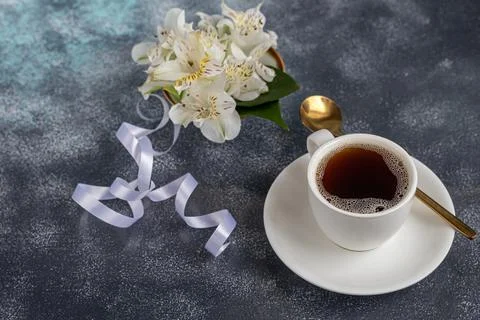 White cup with coffee on a gray background. A bouquet of orchids entwined wit Foto stock