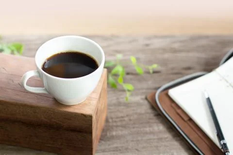 White cup coffee with note book on wooden top table Stock Photos