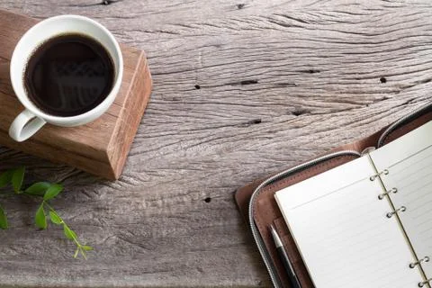 White cup coffee with note book on wooden top table Stock Photos