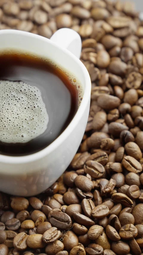 White cup of coffee on rotating table with coffee beans around. Fresh americano. Video stock 303699808