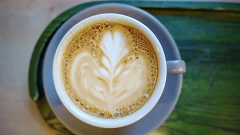 White cup of coffee served with latte art on the table at coffee shop, top shot. Vídeo Stock 334648718