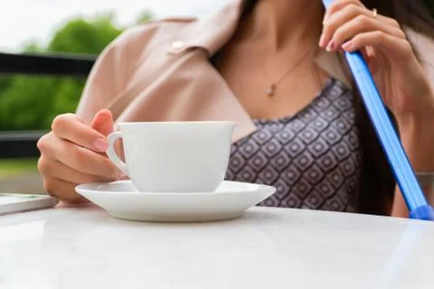 White cup of coffee on a white table. The girl on the terrace smokes a hookah Photos
