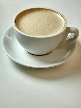 White cup with coffee on a white table. Coffee in a white cup Stock Photos