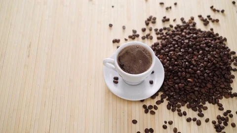 A white cup of evaporating coffee on the table with roasted beans in 4K 库存影片 70161995