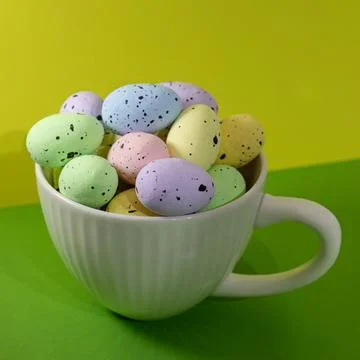 A white cup filled with colorful Easter eggs Stock Photos