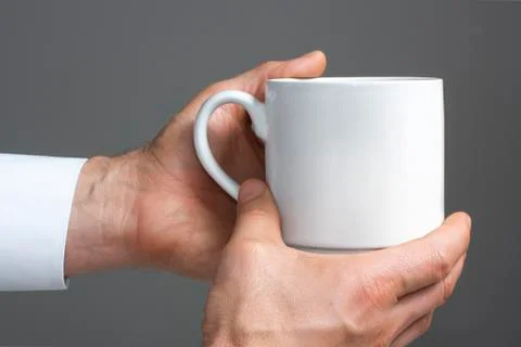 White cup in a hand. Stock Photos