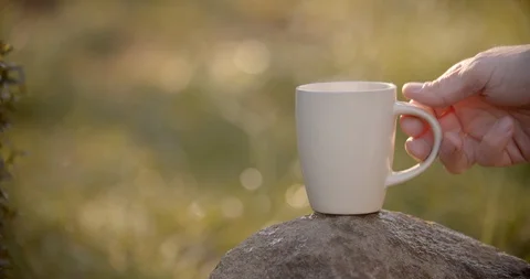 White cup of hot drink, taking cup from the rock. Self-isolation in countryside. Stock Footage 128325025