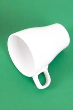 White cup lying on a green background Foto stock