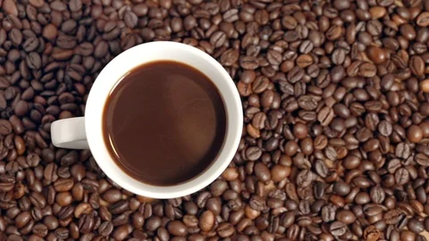 White cup (mug) filled with black coffe lying on roasted coffe beans in a café. Stock Footage 104403437