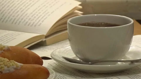 A white cup of really hot smoking coffee with open book on background Stock Footage 54539258