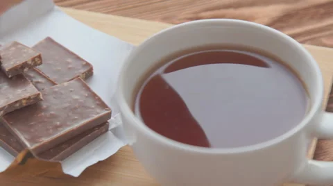 A white cup of really hot smoking tea with bar of chocolate Stock Footage 68974550