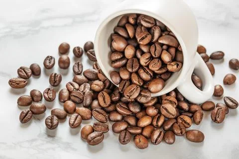 White cup with roasted coffee beans close up, white background. Good mood Stock Photos