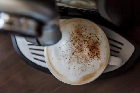 White cup standing on the grating of coffee machine with coffee pouring in th Stock Photos