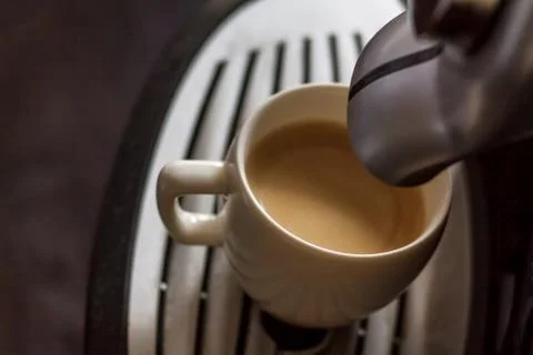 White cup standing on the grating of coffee machine with coffee pouring in th Stock Photos
