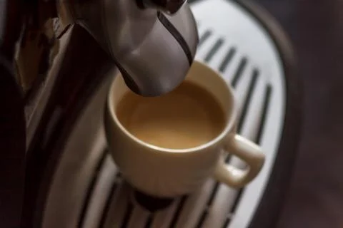 White cup standing on the grating of coffee machine with coffee pouring in th Stock Photos