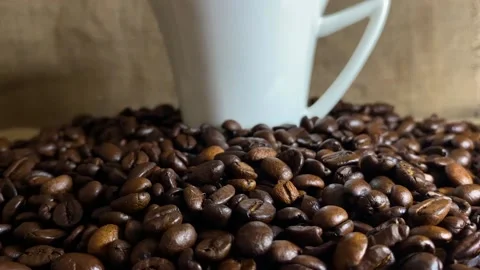White cup standing in the middle of coffee beans, slow motion close up Stock Footage 232873385