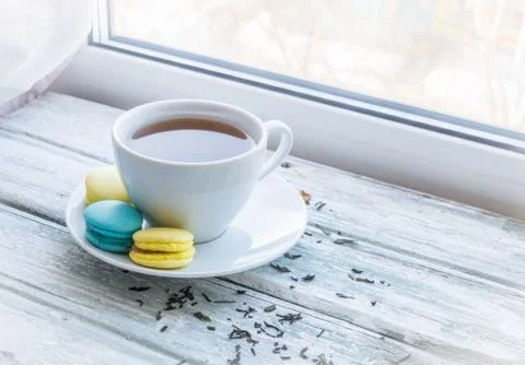 White cup of tea and macarons near the window Stock Photos