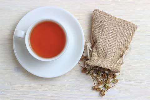 White cup of tea with chamomile in a pouch on a white wooden background Stock Photos