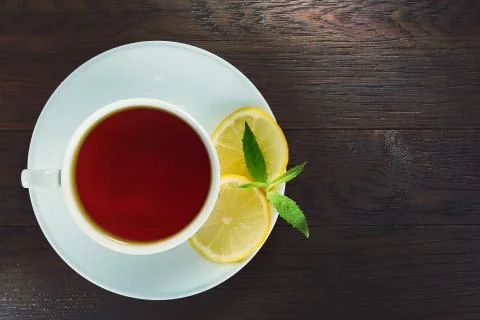 White cup of tea with cinnamon sticks, lemon, mint leaves and tea strainer on Stock Photos