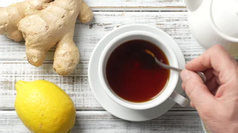 White cup of tea with lemon and ginger on wooden table, top view Stock Footage 185536894