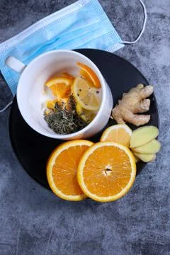White cup of tea with lemon, ginger, orange, jam on the dark grey background. Foto stock