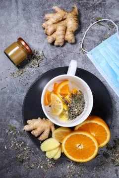 White cup of tea with lemon, ginger, orange, jam on the dark grey background. Stock Photos