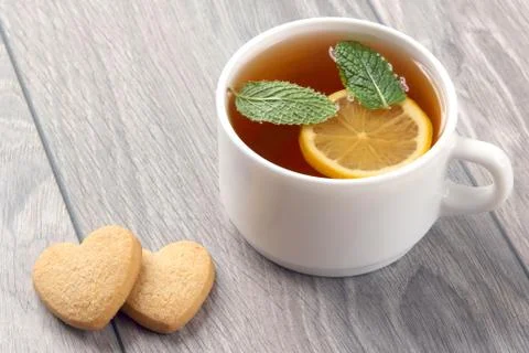 White cup of tea with lemon, mint and cookies on a wooden table Stock Photos