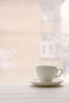 White cup in window sill on a background of house and snowy weather. Stock Photos