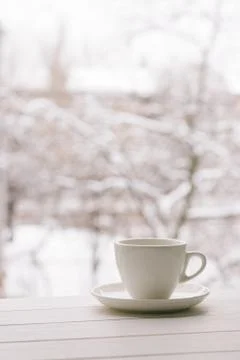 White cup in window sill on a background of snowy weather. Stock Photos