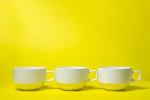White cups on a yellow background.  Stock Photos