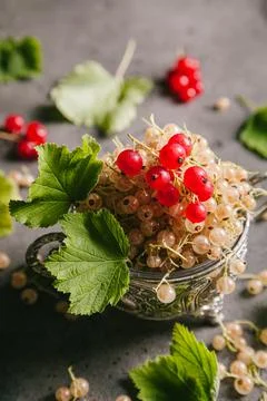 White currant and red currant with leaves in a metal vintage bowl on a gray b Stock Photos
