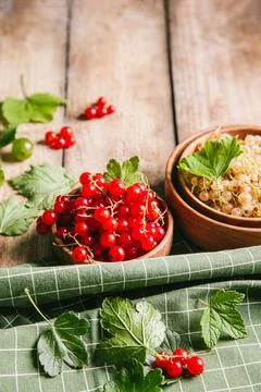 White currant and red currant with leaves in wooden bowls on a wooden backgro Stock Photos